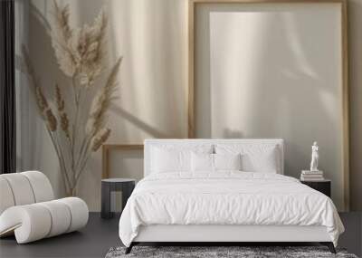 Two white frames with a white background and a vase of dried grass in between Wall mural