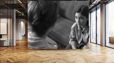 Two young ladies in a living room, engaged in an intimate discussion. They're seated on a couch in a casual and comfortable environment. Wall mural