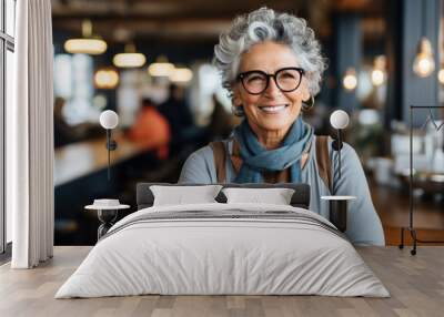 Woman wearing glasses and scarf standing in restaurant. This image can be used to showcase stylish and confident woman in trendy restaurant setting. Wall mural