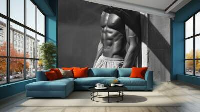 Young athlete posing in shadow with muscular build, wearing sportswear. Concept of health and fitness. Wall mural