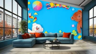 Baby kids toys background. Two teddy bears, wooden train, toy cars, colorful blocks on blue background Wall mural