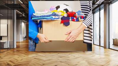 Donation concept. Donate box with clothes, books and toys in child and mother hand Wall mural