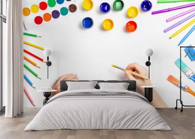 Kid hands painting at the table with art supplies, top view Wall mural