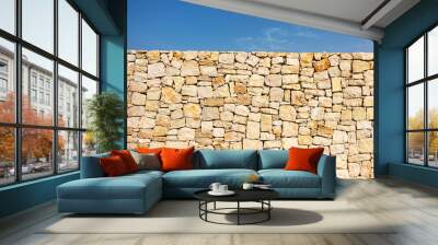 Old brown masonry wall of stones and blue sky background. Low angle view Wall mural