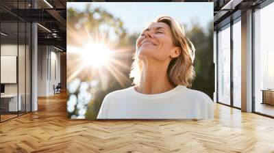 Portrait of happy mature woman enjoying wonderful sunny day in nature Wall mural