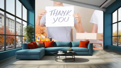 Thank you for donation. Volunteers collecting donations for charity. Teenagers holding paper sheet with message Thank you over cardboard boxes full of food glocery, clothes, toys Wall mural