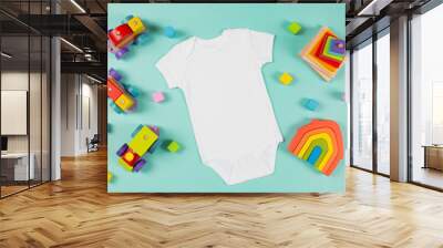 White cotton baby short sleeve bodysuit and natural wooden eco-friendly educational toys on green background. Infant onesie mockup. Blank gender neutral newborn bodysuit template mock up. Top view Wall mural