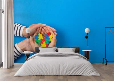 World autism awareness day concept. Adult and child hands holding puzzle heart on light blue background Wall mural