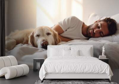 Young man and dog sleeping together in white bed at home Wall mural