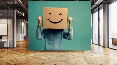 Young man standing and gesturing with brown cardboard box with smiley face on his head. Funny person doing winner gesture and celebrating. Victory, happiness, success concept Wall mural