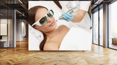 beautiful woman lying in medical cosmetology center and receiving laser procedures Wall mural