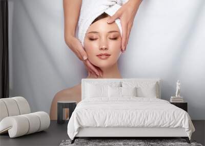 beauty master holding woman's face that lying down on white Wall mural