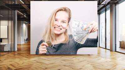 girl emotionally demonstrates bitcoin and dollars to the cryptocurrency coin. Concept of victory and success in business and economics. Wall mural