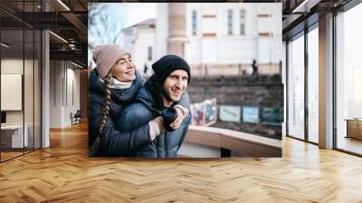 Loving couple in winter clothes and knitted hats walk around the city in the winter before Christmas and New Year. Wall mural