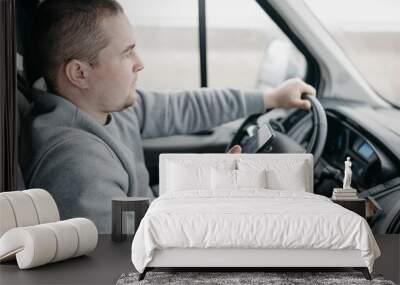 male truck driver uses smartphone while sitting in cab. Wall mural