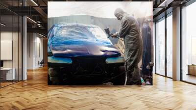 Master car painter paints a car with a spray gun. Car painting at home. Wall mural