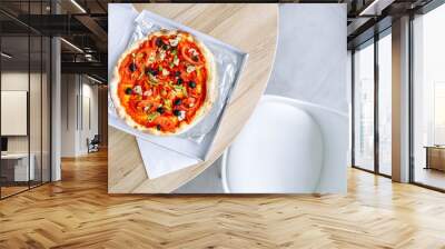 vegetarian pizza with tomatoes peppers and olives in a delivery box on the table in the office Wall mural