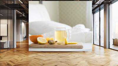 Cup with antipyretic drugs for colds,flu.Tea with citrus vitamin C,ginger root,lemon,orange.Wooden tray in patient's bed. Home self-treatment.Medical quarantine antiviral covid-19 coronavirus therapy Wall mural