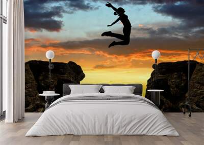 Silhouette the girl jumping over the gap at sunset Wall mural