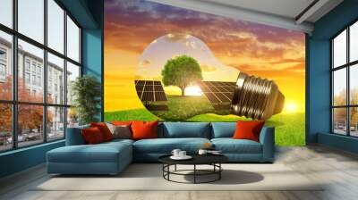 Solar energy panels in light bulb at sunset. The concept of sustainable resources. Wall mural