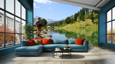 Woman tourist at the beautiful mountain lake in Neouvielle national nature reserve, Lac de Bastan inferieur, French Pyrenees. Wall mural