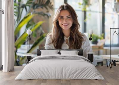 Cheerful young woman working at a desk in a bright creative office background is clear and clean Wall mural