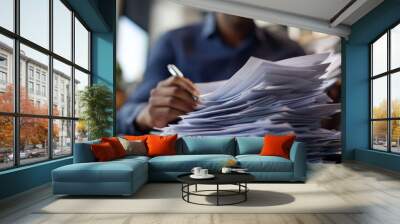 Employee sorting through a stack of documents while seated at a modern office table Wall mural