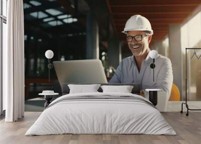 Mature architect wearing white construction helmet and safety working on laptop in construction area Wall mural