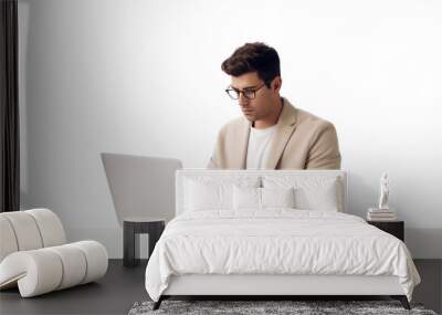 Young man working intently on laptop, working remotely online on a white background Wall mural