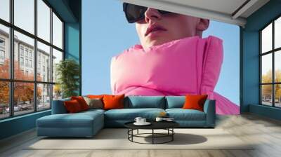 A man wearing a pink jacket and white hat and wearing sunglasses Wall mural