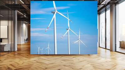 Fleet of power generators in motion. The blades of the wind farm rotate against the sky. The concept of extracting electricity from renewable sources. Wind turbine to generate electricity. Wall mural