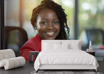 smiling young African-American businesswoman happily working at her desk in a comfortably air-conditioned office. Wall mural