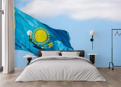 The flag of Kazakhstan is fluttering in the wind against the blue sky. The flag is located on the blue dome of the administrative building. The city of Astana is the administrative center. Wall mural