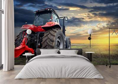 Agricultural tractor working in the field at sunset background Wall mural