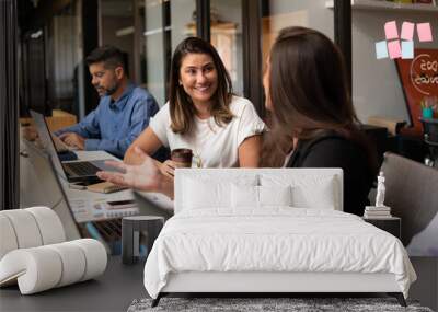 brazilian woman talking causally with co-worker in workstation. . Wall mural