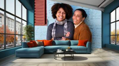 Happy cheerful black adult daughter and mother with broad smile embracing each other outside humble home Togetherness, family, support concept. Wall mural