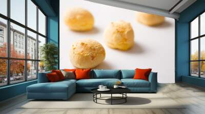 Pao de Queijo is a cheese bread ball from Brazil. Also known as Chipa, Pandebono and Pan de Yuca. Snacks spread over white table. Minimalism and selective focus. Wall mural