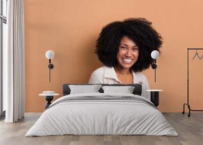 shy african american woman smiling and standing wearing white jacket in beige background. portrait, real people concept. Wall mural