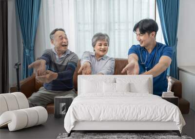 a young male assistant in uniform advice and help asian senior couple arm stretch exercise in the room,health care worker nurse visit at patient home,concept of elderly care,home care Wall mural