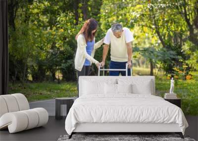 caregiver takes disability senior man practice walking with walker in the park Wall mural