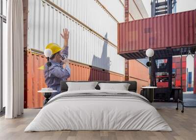 foreman control loading containers box from cargo freight ship,holding walkie talkie and hand up for direction the forklift handling container stacker craine,container worker working at dock site Wall mural