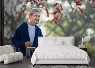 portrait happy senior man with grey hair and beard  in sportswear exercising in the park during sunrise Wall mural