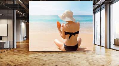 Beautiful woman in bikini applying sun cream on tanned shoulder. Sun protection. Skin and body care. Wall mural