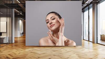 Beautiful young woman with clean perfect skin. Portrait of beauty model with natural nude make up and touching her face. Spa, skincare and wellness. Close up, copyspace. Wall mural