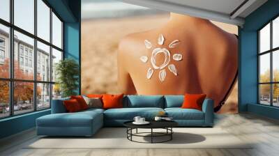 Skin care. Sun protection. Woman apply sun cream. Woman With Suntan Lotion On Beach In Form Of The Sun. Portrait Of Female With  Drawn Sun On A Shoulder. Suncream. Girl Holding Moisturizing Sunblock. Wall mural