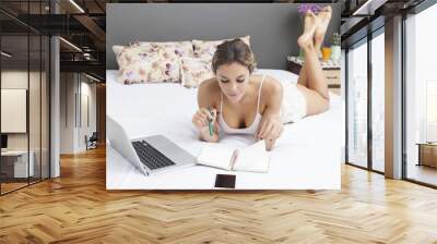 Young sensual latin woman relaxing in bed with laptop Wall mural