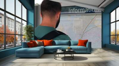 Man looking at the information board with a city map, direction planning Wall mural