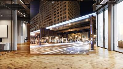 view of a train over a street and car lights at night in a city Wall mural