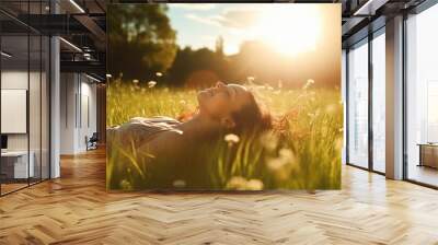 Cheerful young woman smiling and enjoying in the sunset. Woman lying on the grass young woman laying in a field of bluebonnet wildflowers Wall mural