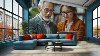 A man and woman look at a tablet. Wall mural